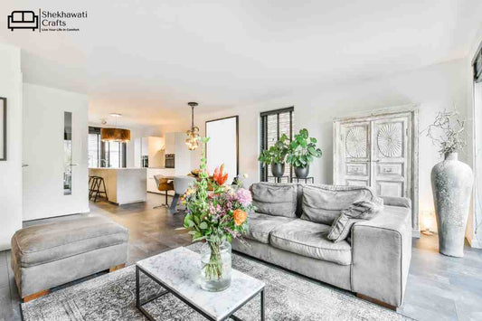 A living room image featuring a sofa, a wooden almirah, a center table and various decorative accessories.