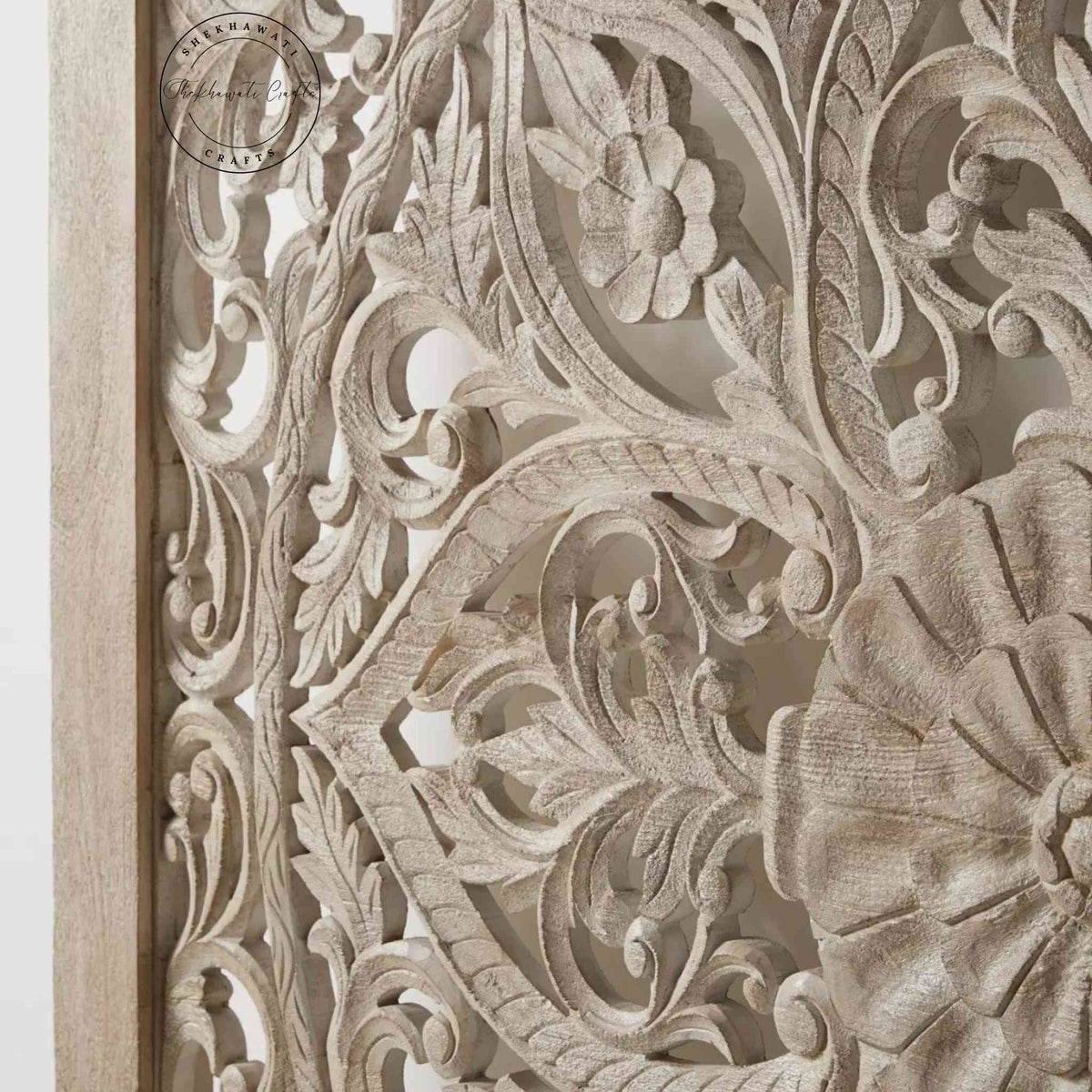 Close-up view of a king-size wooden bed with hand carvings on the headboard and painted in a rustic white finish.