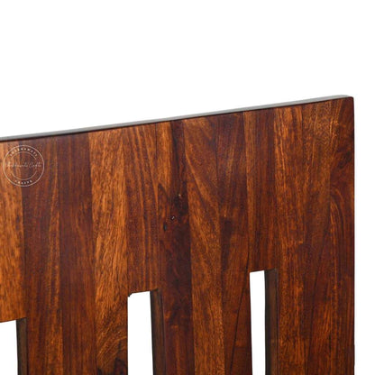 Close-up view of a dark brown wooden chair backrest with vertical slats and visible wood grain, photographed against a white background.