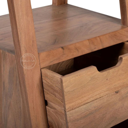 Close-up of a wooden storage shelf with a drawer, showing warm medium-brown wood grain and a pull-tab drawer design.