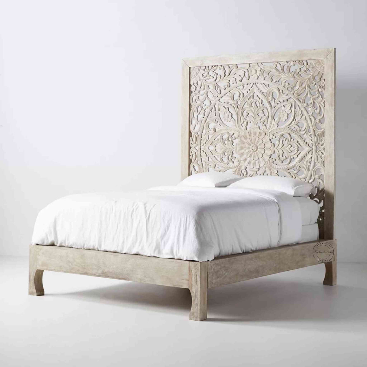 Side view of a king-size wooden bed with hand carvings on the headboard, painted in a rustic white finish.