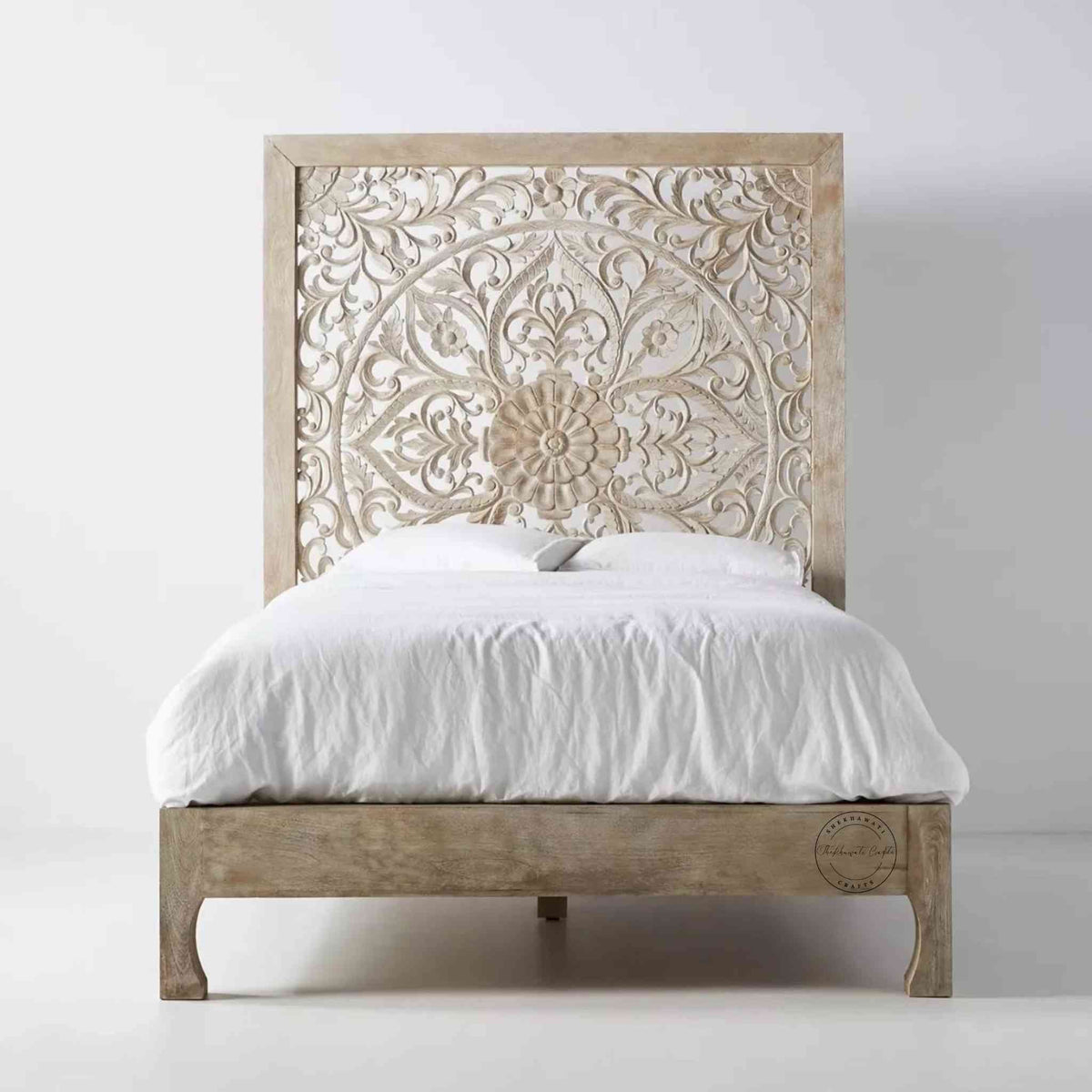 A king-size wooden bed with hand carvings on the headboard, painted in a rustic white finish.