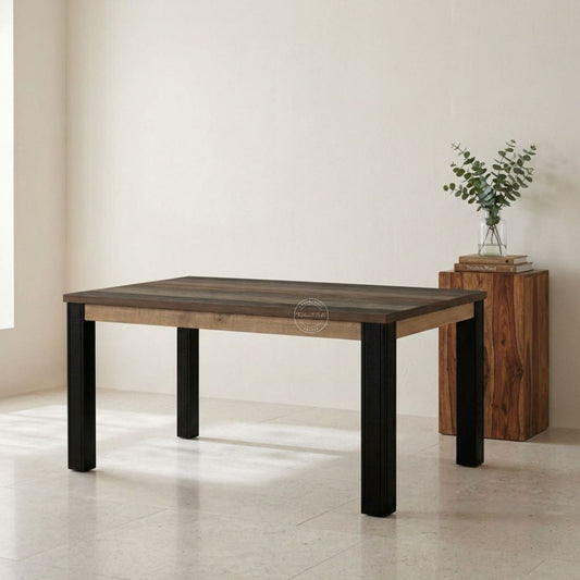 A rectangular dining table with a dark brown wood top, a light natural wood apron, and black wooden legs, shown in a minimalist room setting next to a wooden sideboard.