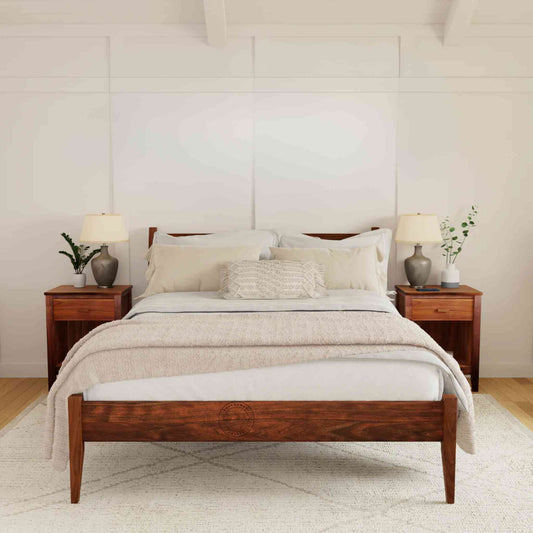 A king size bed made of Sheesham wood with a curved headboard, shown in a bedroom setting with bedside tables and lamps.