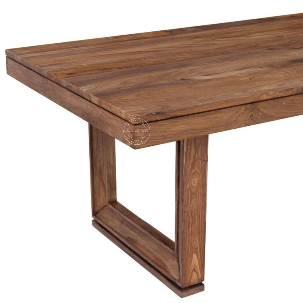 A close-up view of wooden dining table with a rich brown grain, featuring a rectangular top and a geometric, open-frame leg base, shown against a plain white background.