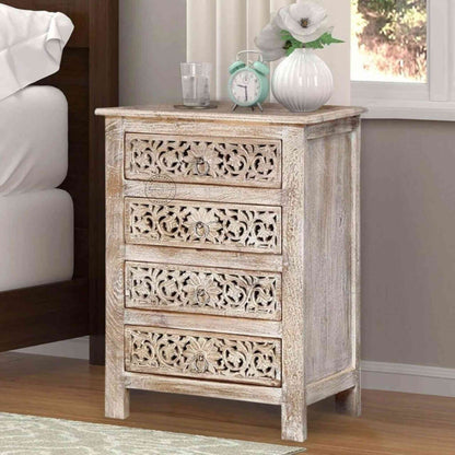 A beige wooden bedside table with four drawers, featuring traditional floral carved designs.