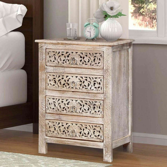 A beige wooden bedside table with four drawers, featuring traditional floral carved designs.