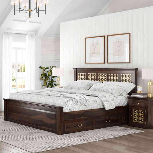 A king size wooden bed with brass inlays and storage drawers, in a room with light walls.