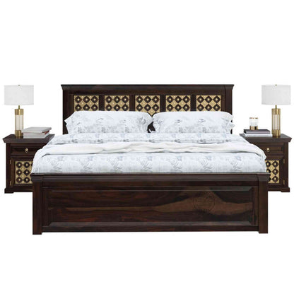 A king size wooden bed with brass inlays and storage drawers, in a room with light walls.