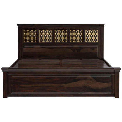 A king size wooden bed with brass inlays and storage drawers, in a room with light walls.