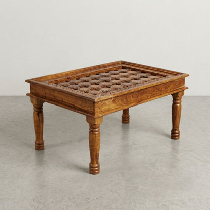 A rectangular wooden coffee table with hand-carved details on top, turned legs, and a warm medium-brown finish.