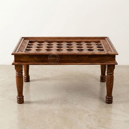 A rectangular wooden coffee table with hand-carved details on top, turned legs, and a warm medium-brown finish.