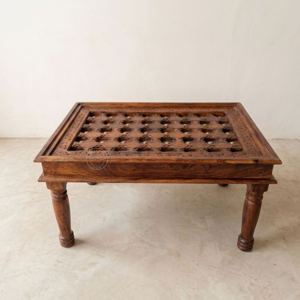 A rectangular dark brown wooden table with carved details and a grid of circular cutouts on the top, supported by four turned legs.