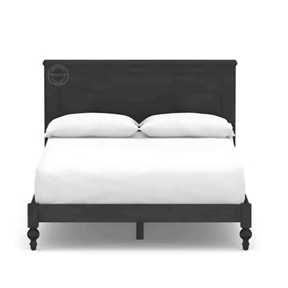 A wooden king size bed with a dark wooden headboard and footboard, dressed with white bedding.