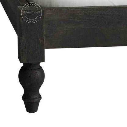 Close-up view of a wooden king size bed footboard and round leg.