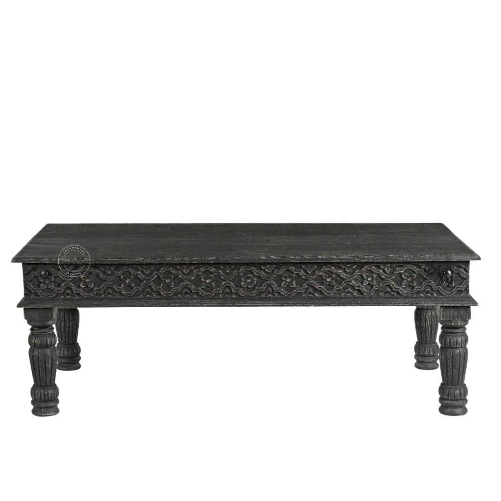 A rectangular black carved wooden coffee table with ornate detailing on the apron and turned legs, shown against a plain white background.