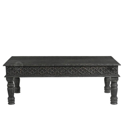 A rectangular black carved wooden coffee table with ornate detailing on the apron and turned legs, shown against a plain white background.