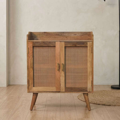 A accent modern wooden cabinet with two cane doors and tapered wooden legs, set against a neutral textured wall and light wood floor.
