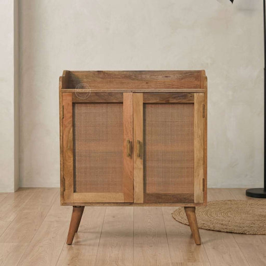 A accent modern wooden cabinet with two cane doors and tapered wooden legs, set against a neutral textured wall and light wood floor.