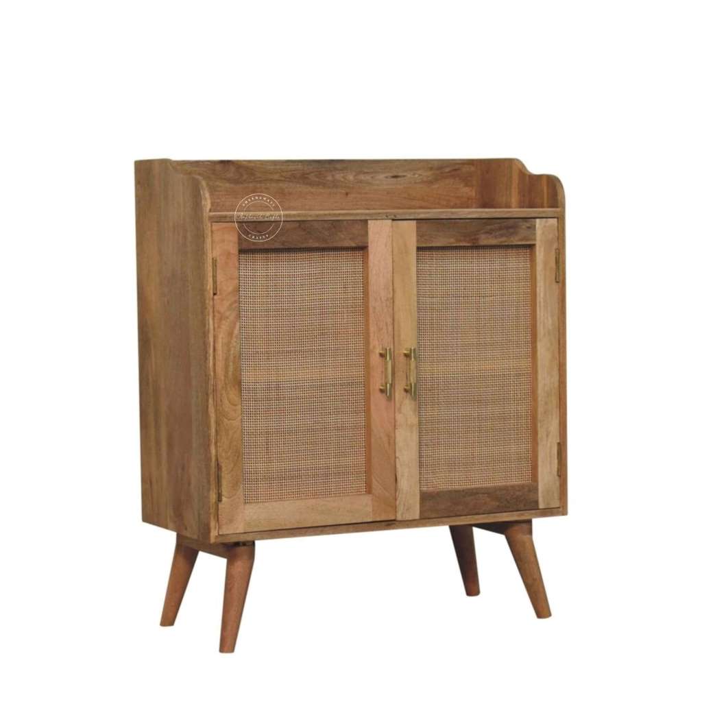 A mid-century modern wooden cabinet with two cane doors, brass handles, and tapered wooden legs, shown on a plain white background.