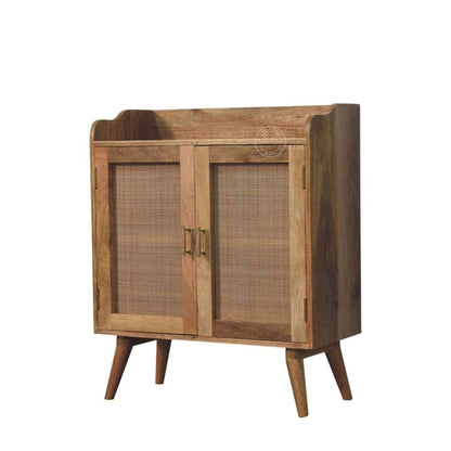 A mid-century modern wooden cabinet with two doors featuring woven cane panels, brass handles, and tapered wooden legs, shown against a plain white background.